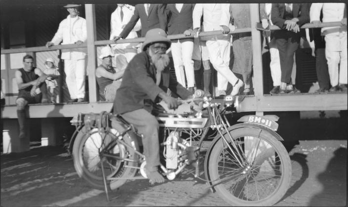 A man on a bike in front of a hotel. 